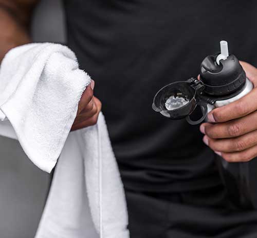 man holding towel and water bottle before workout