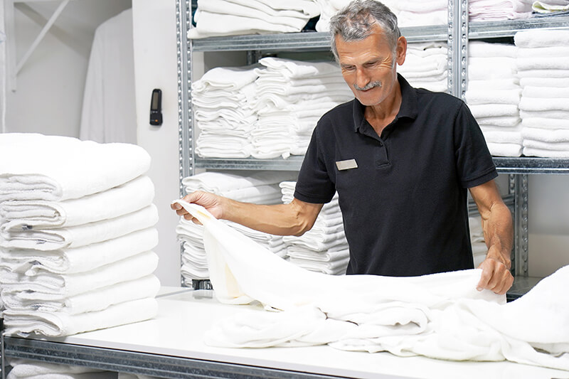 Worker Folds Freshly Washed Towels In Bulk